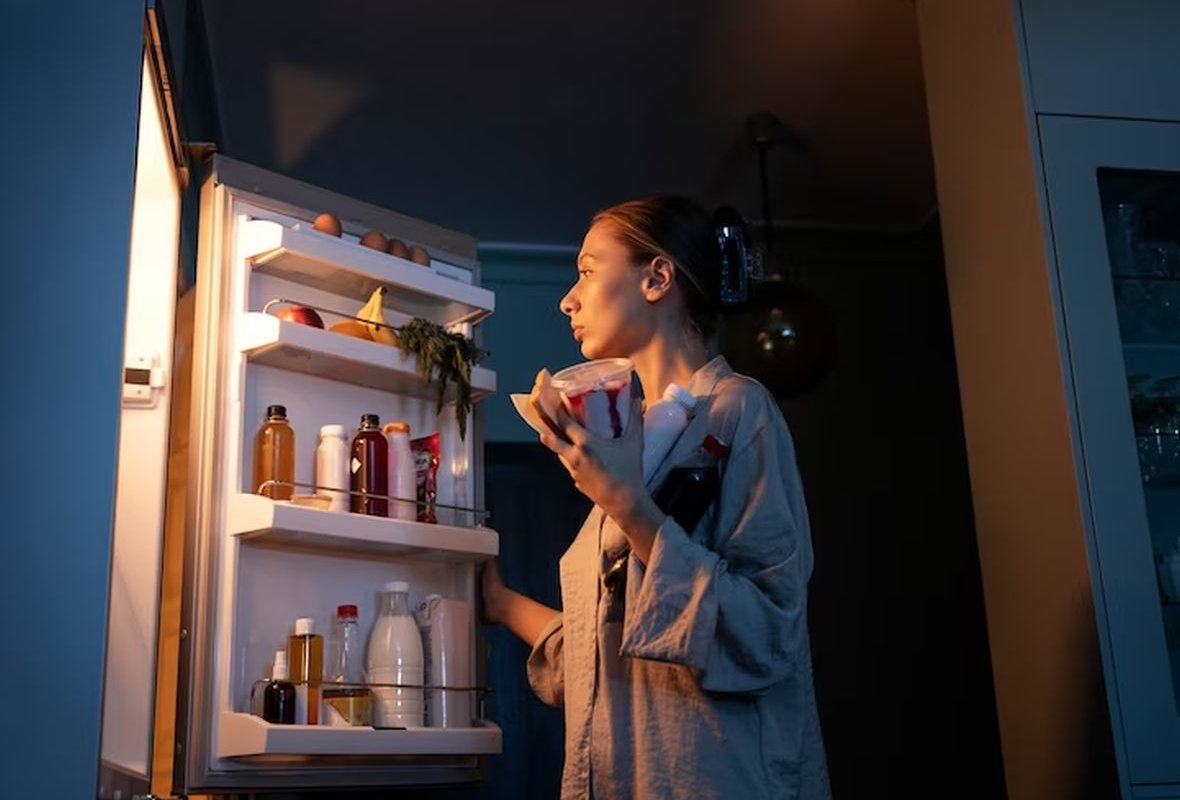 a woman is standing by the refrigerator