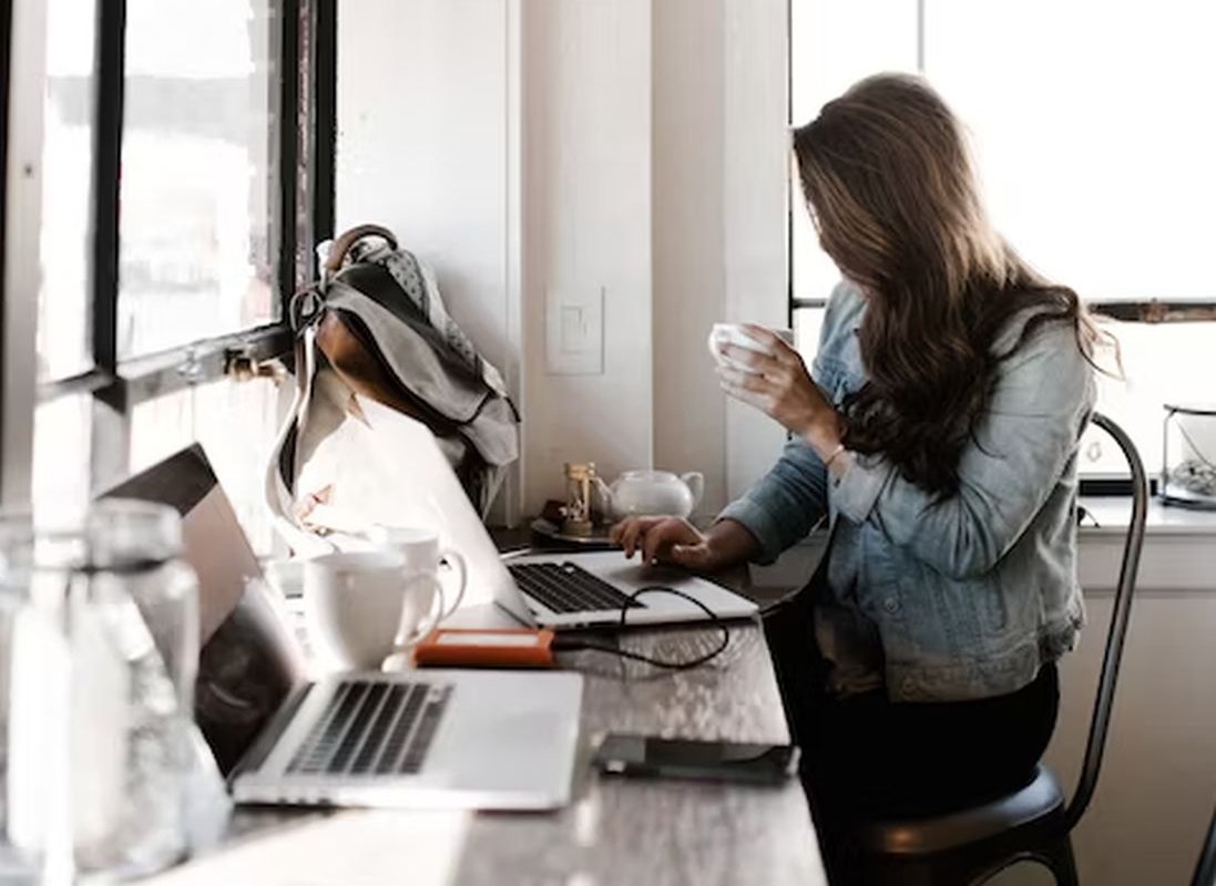 a woman sits at a laptop