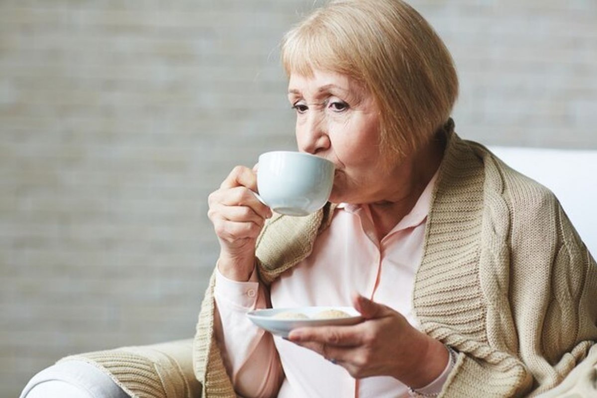 an elderly woman drinks tea